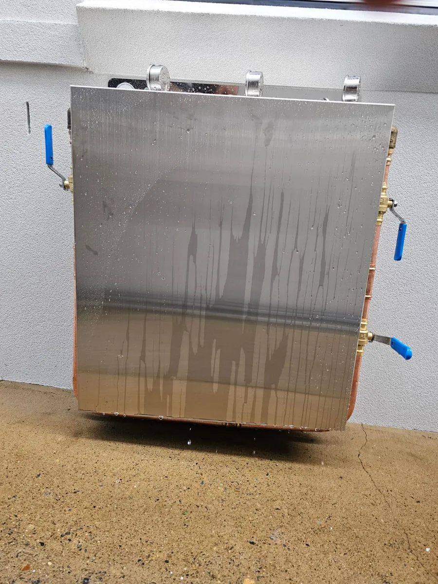 Whole house filtration system with stainless cover installed on a driveway wall